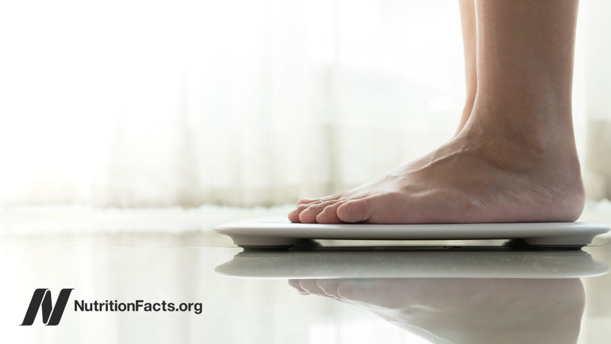 Feet placed on a weight scale from the side in front of a light background