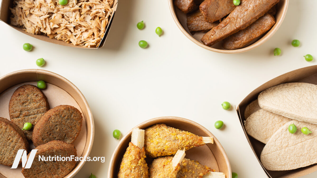 Paper containers holding plant based meat alternatives with several peas on white background