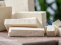 Tofu sliced and cubed on a cutting board