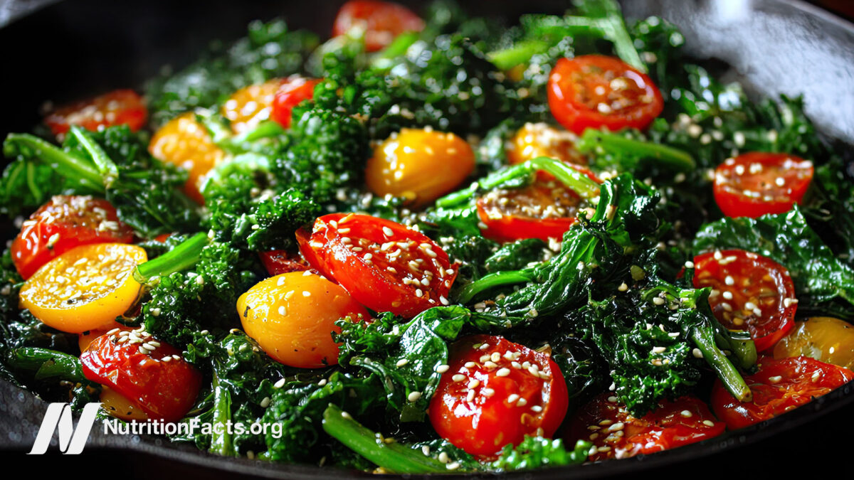 A mixed greens and tomato sauté in a pan