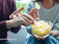A couple sharing potato chips in a bowl