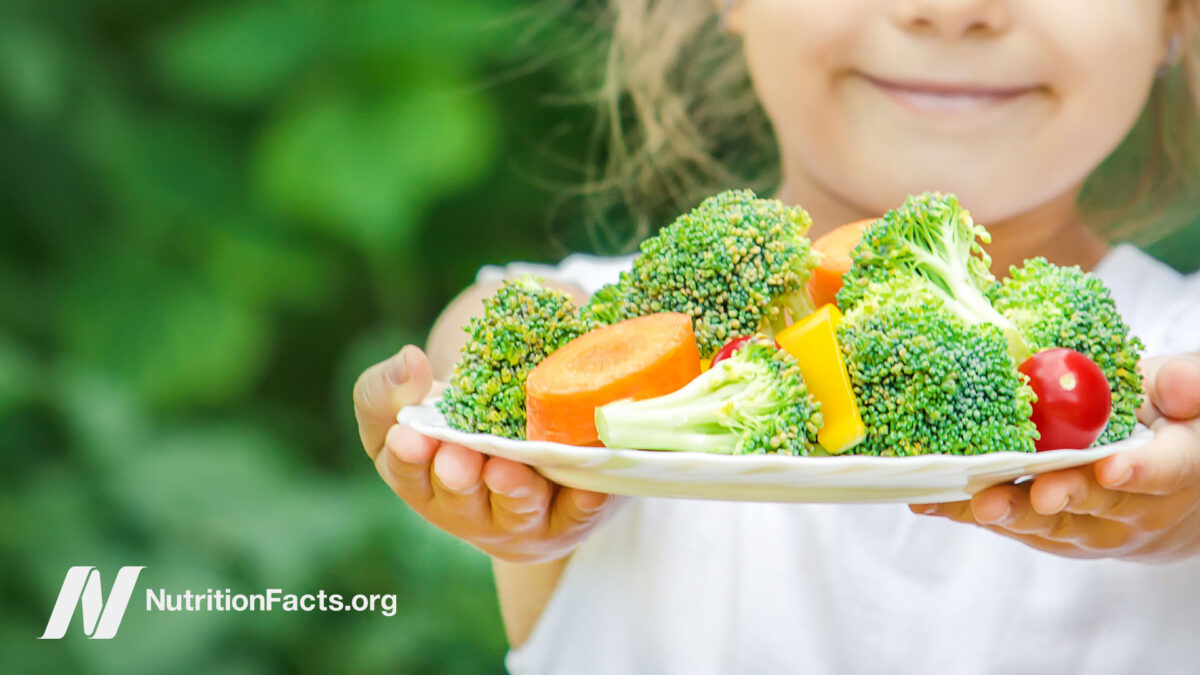 Child holding out a plate of fresh vegetables