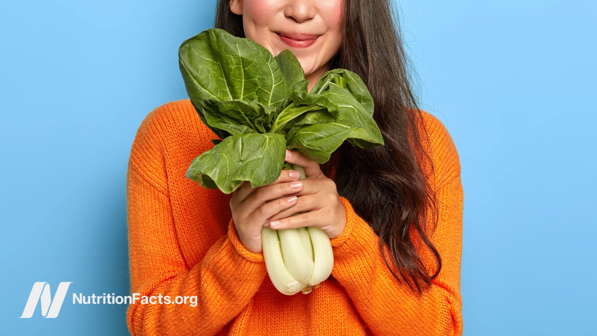 Woman cheerfully holding bok choy